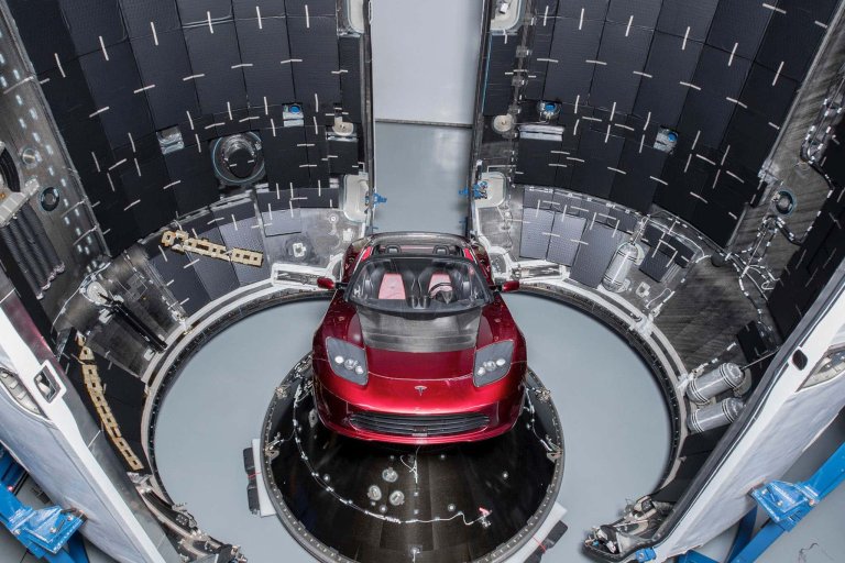 Red Tesla Roadster being loaded into a rocket capsule during Elon Musk's SpaceX launch in 2018
