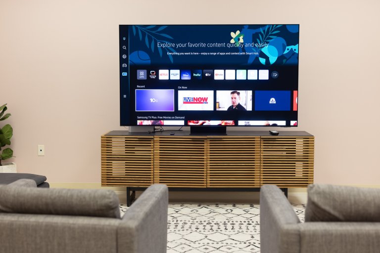 The Samsung S95C OLED on a stand in a room with two chairs
