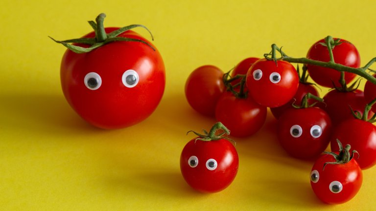 Red tomatoes with googly eyes on yellow background