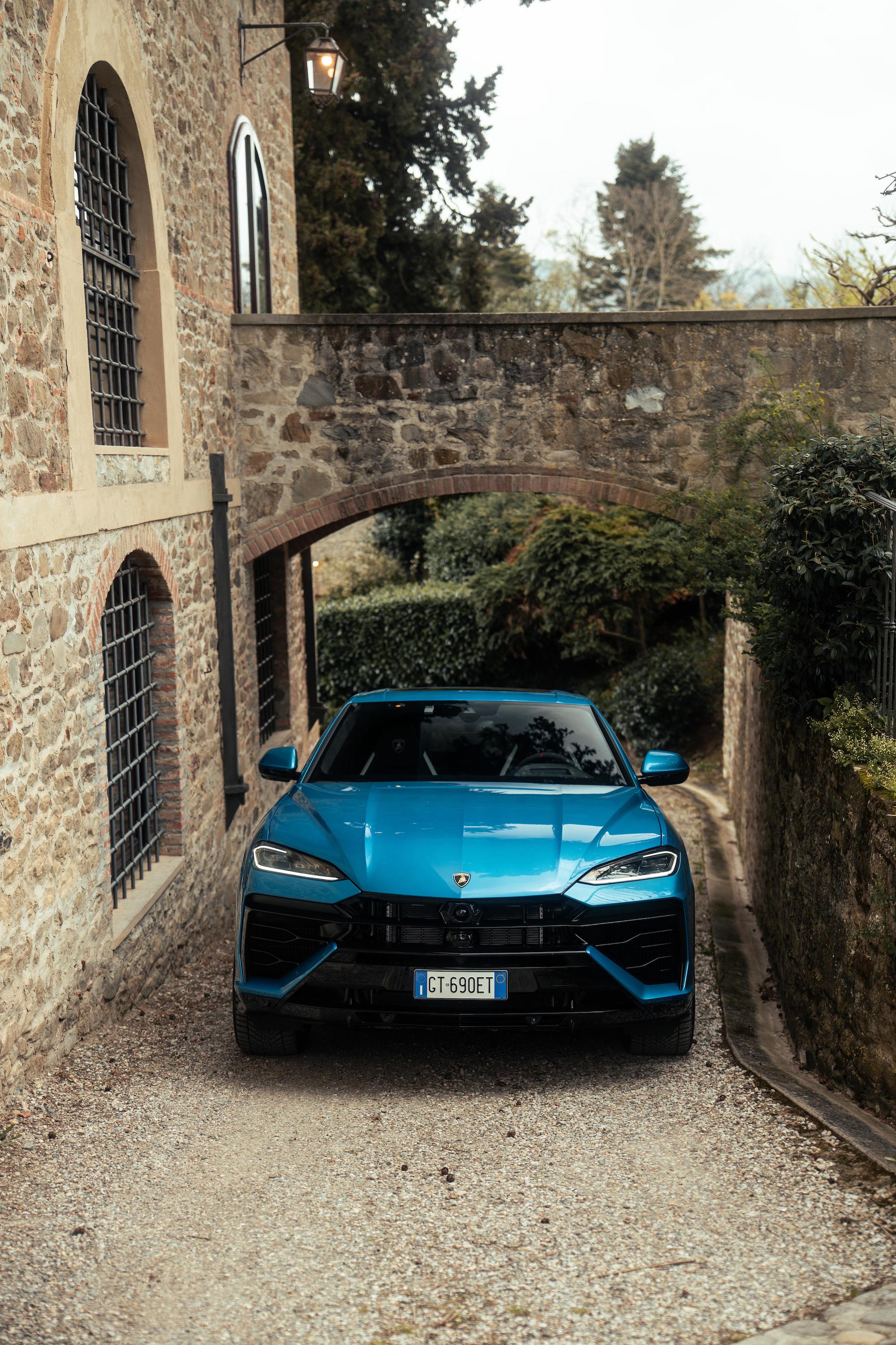 blue car driving up gravel drive